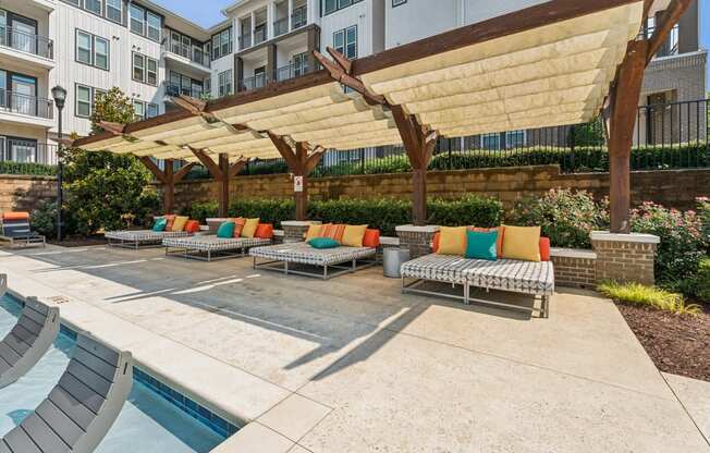 a group of lounge chairs under a large canopy next to a pool