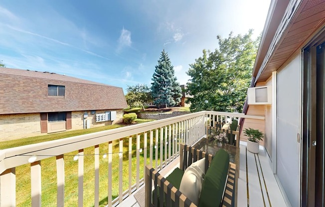 A balcony with a white railing and a green cushioned chair.
