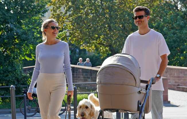 a couple walking a dog and a baby stroller