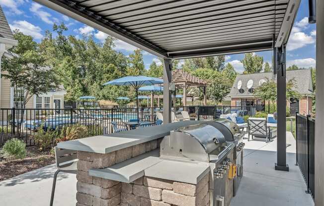 an outdoor patio with a grill and a pool with umbrellas