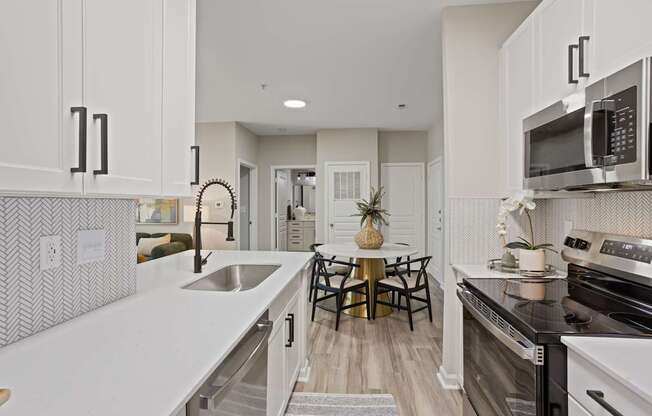 Flatiron West Trade Apartments staged model unit kitchen connected to living room with stainless steel modern appliances and quartz countertops