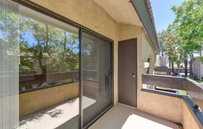 A patio with a sliding glass door and a brown door.