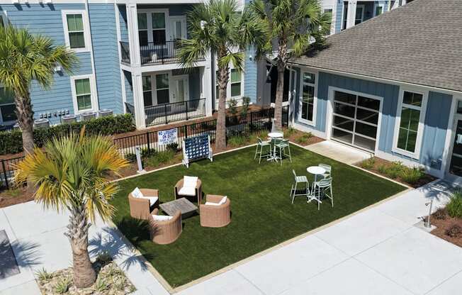 A patio area with a table and chairs surrounded by a grassy area and palm trees.