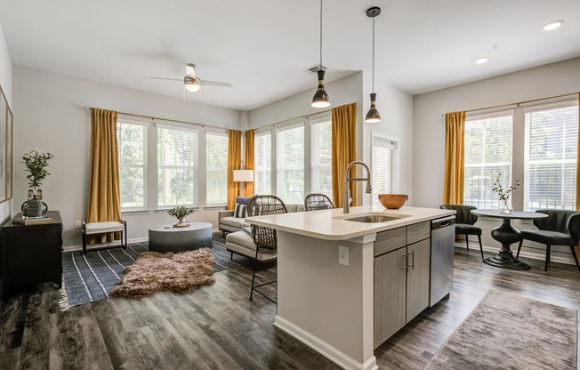 an open floor plan with a kitchen island and a living room with a couch and chairs at Century University City, North Carolina