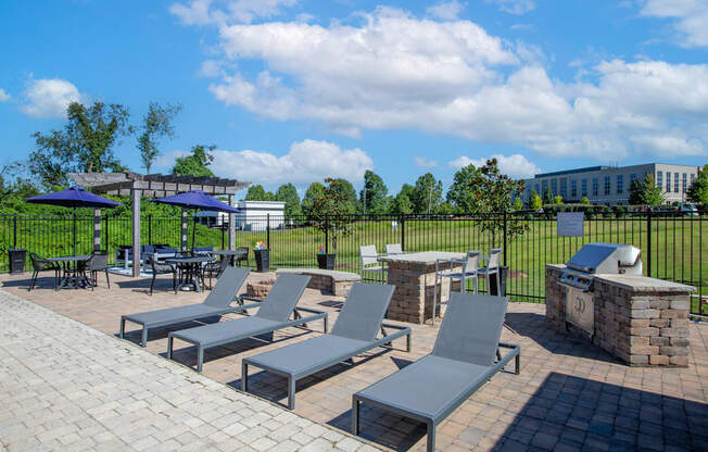 A patio with grey chairs and tables is surrounded by a black fence.