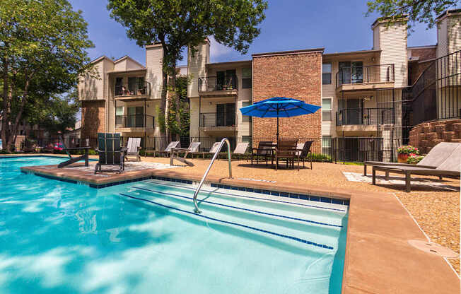 A swimming pool in front of apartment buildings at Canyon Creek Apartments in the Dallas Midtown neighborhood of Dallas, TX.