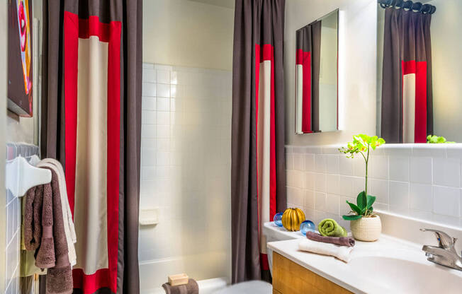 a bathroom with red and white shower curtains and a sink and a toilet