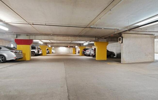A parking garage with a few cars and yellow columns.