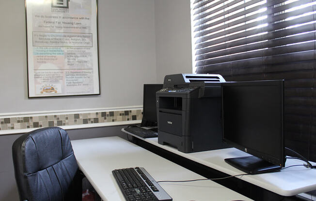 a desk with a computer and a printer on it