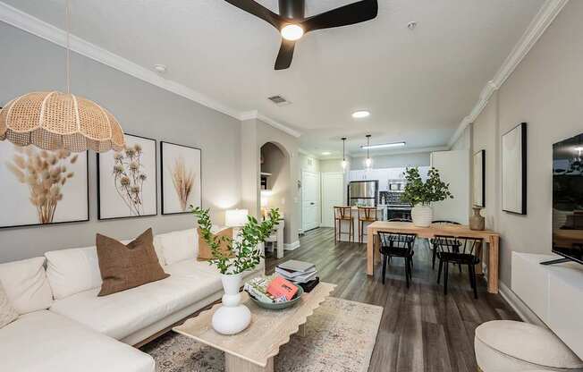 A living room with a white couch, a wooden coffee table, and a ceiling fan.