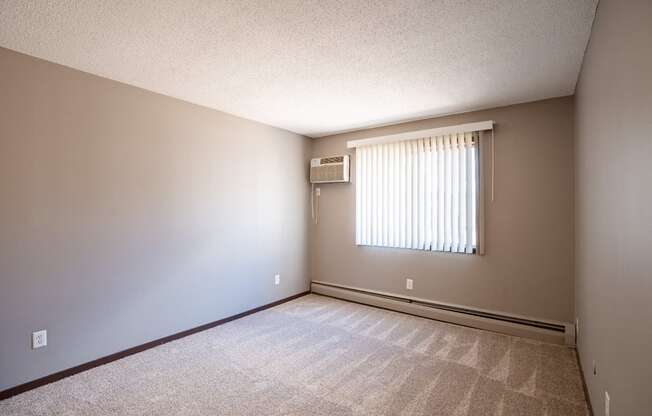 a bedroom of an empty house with a window. Roseville, MN Rosedale Estates Apartments