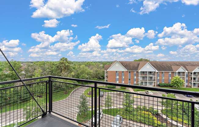 A balcony overlooks a green lawn and a brick building.