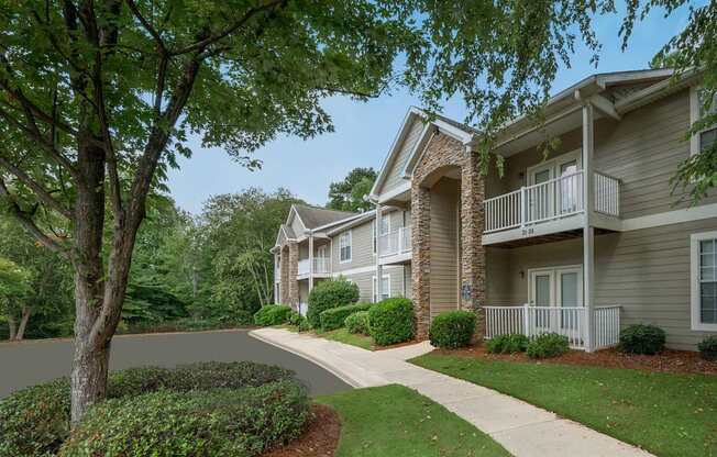 A tree in front of a building with a white fence.