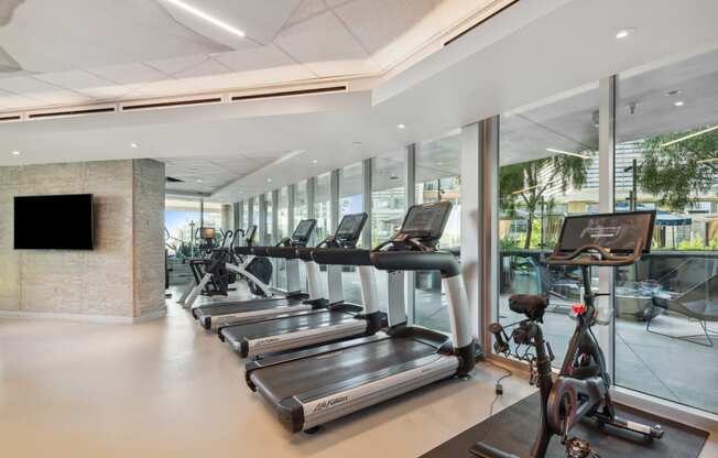 a gym with cardio machines and a television