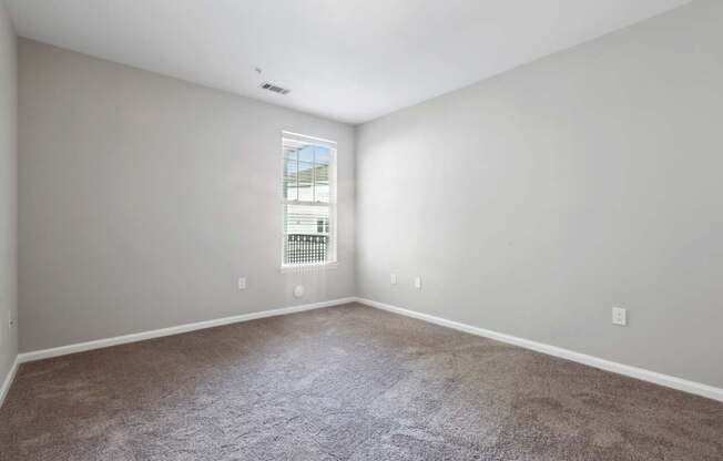 A room with a carpeted floor and a window with blinds.
