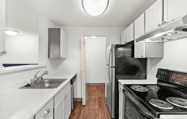 A kitchen with a black refrigerator and stove top oven.