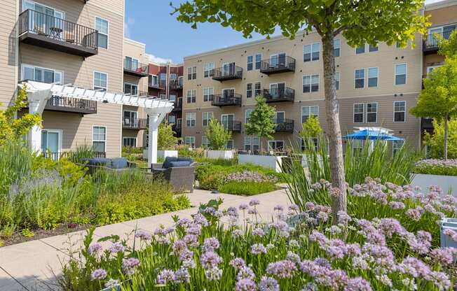 a garden with flowers in front of an apartment building