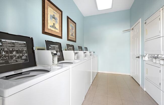 a laundry room with white washers and dryers and blue walls