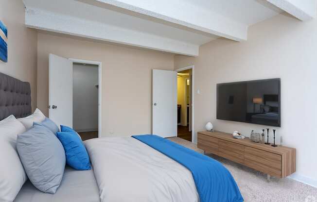 A bedroom with a bed, a couch, and a television.