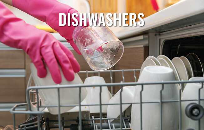 A person in pink gloves is loading dishes into a dishwasher.
