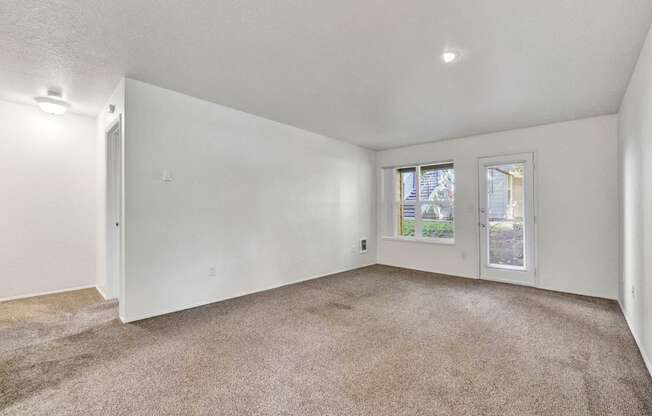 an empty living room with carpet and a window