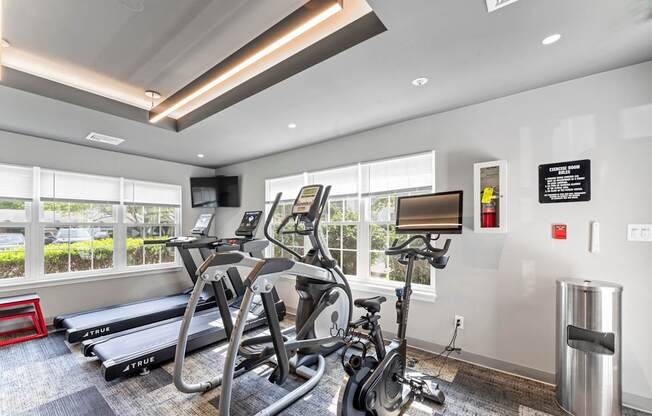 A gym with treadmills, exercise bikes and a TV.