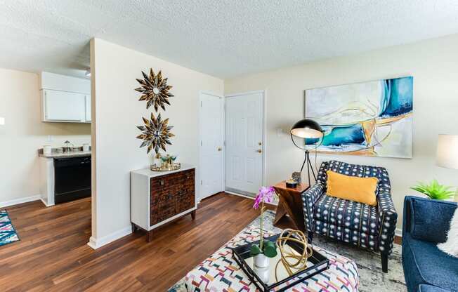 a living room with hardwood floors and a kitchen in the background