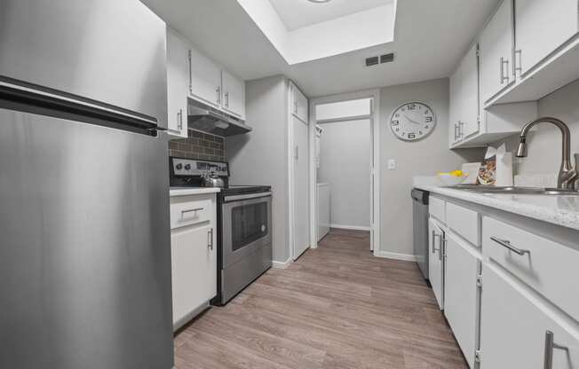 a kitchen with white cabinets and stainless steel appliances and a clock on the wall