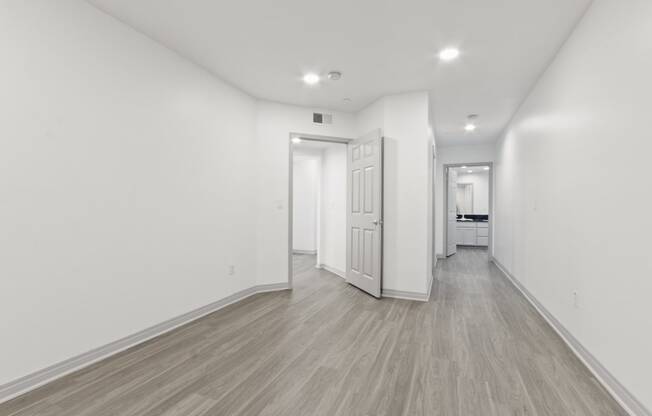 a renovated living room and hallway with white walls and wood floors