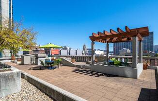 a rooftop patio with a pergola and a view of the city