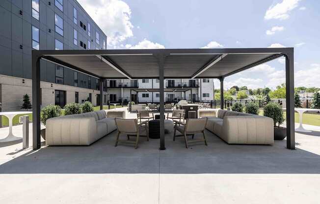 A modern outdoor seating area with white cushioned furniture and a black metal roof.