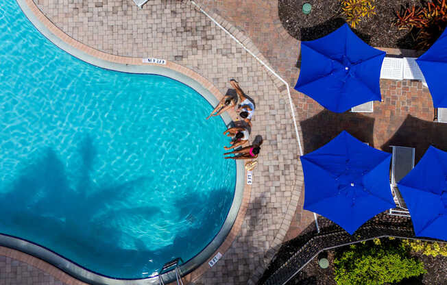 A swimming pool with blue umbrellas and people enjoying the water.