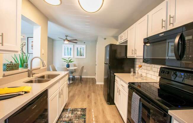 A modern kitchen with black appliances and white cabinets.