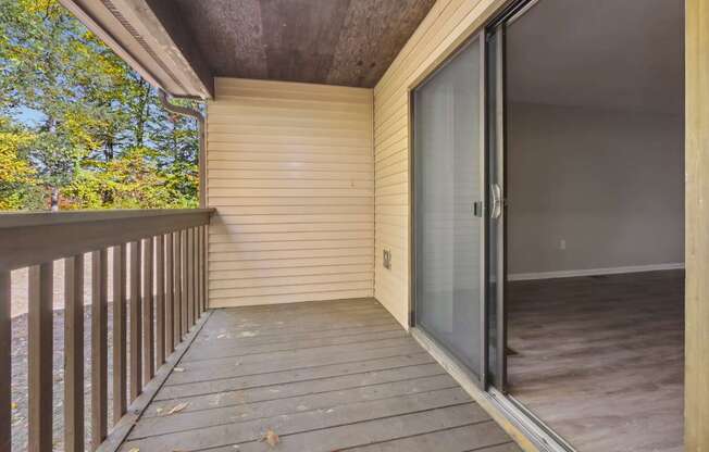 A balcony with a sliding glass door leading to a room.
