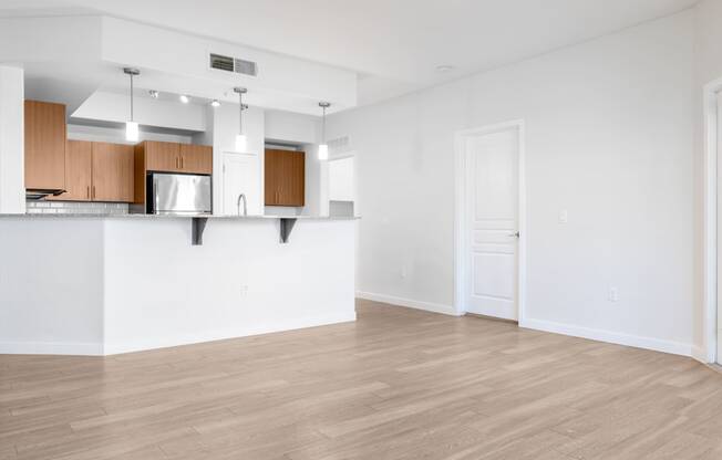 an empty living room and kitchen with white walls and wood floors