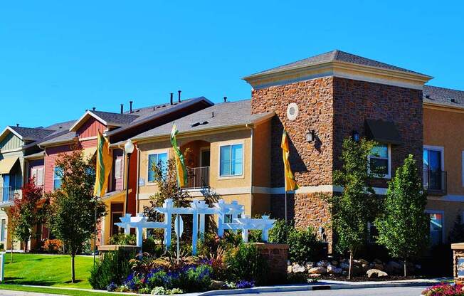 Liberty Landing Apartments entrance with flower beds and white wooden decorative structure. West Jordan, Utah.