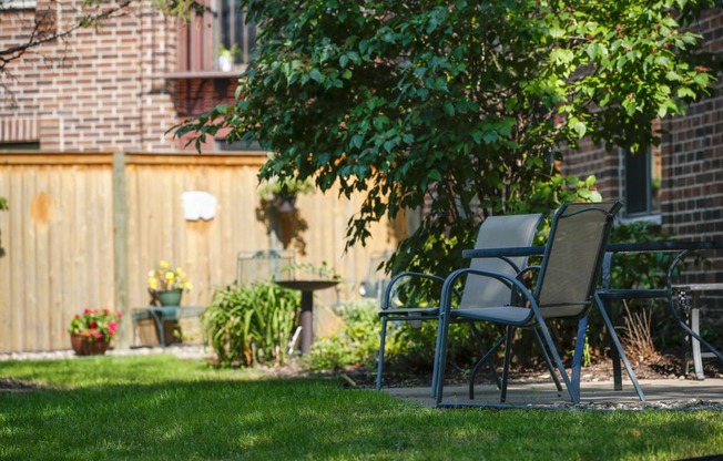a yard with lawn chairs and a tree and a fence