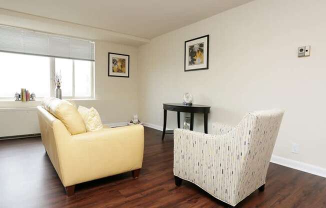 A living room with a yellow couch and a white patterned chair.