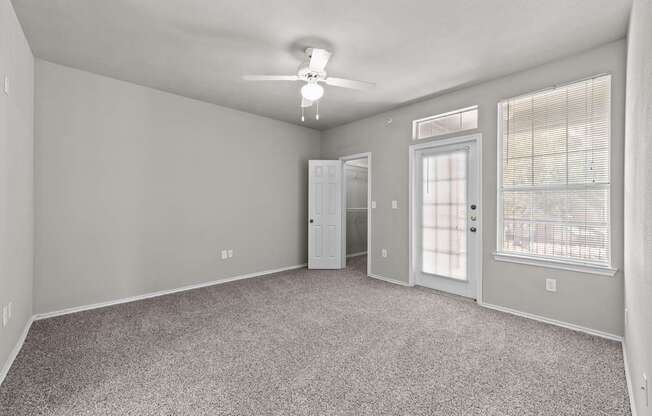 A spacious room with a carpeted floor and a ceiling fan.