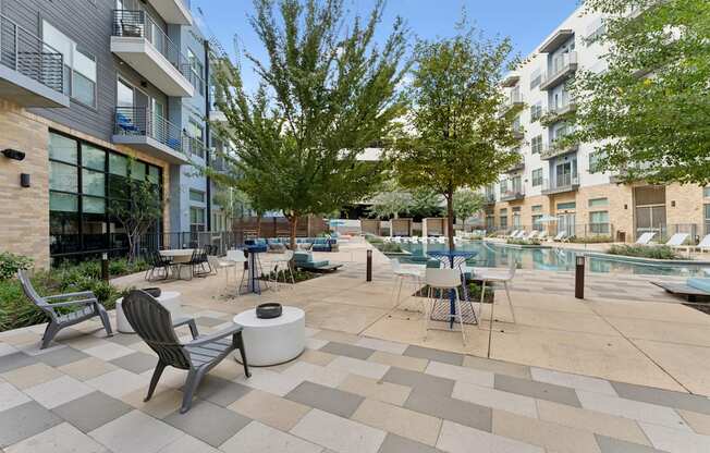 A patio with a table and chairs is surrounded by apartment buildings.