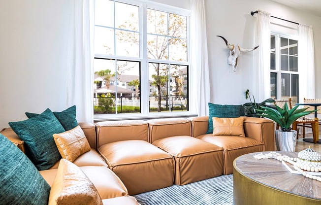 Living room with a brown couch and a large window at The Parker Austin, Pflugerville, Texas