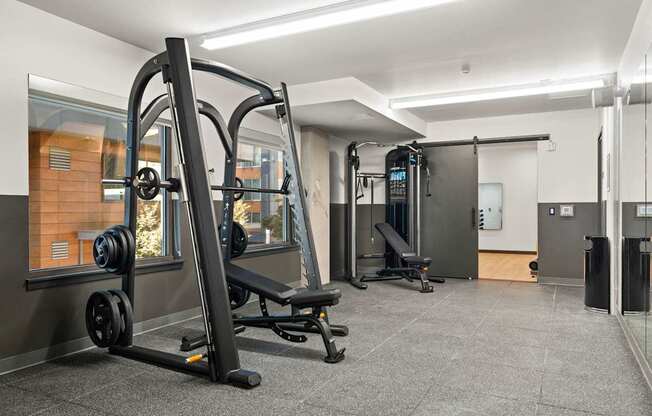 A gym with a variety of equipment including a squat rack, bench, and weights.