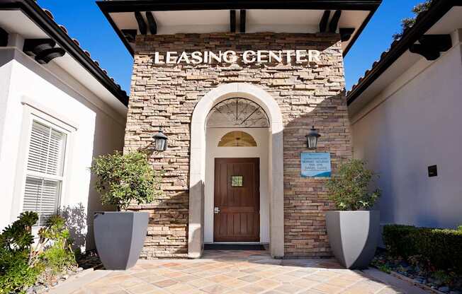 A leasing center with a brown door and a stone wall.