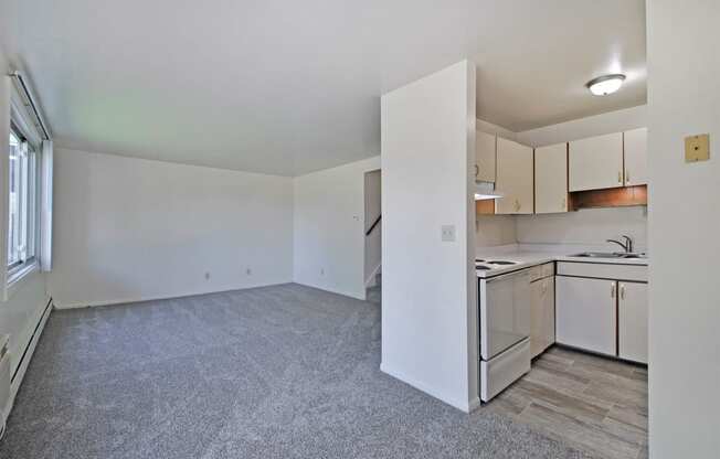 the spacious living room and kitchen with white cabinets and white appliances