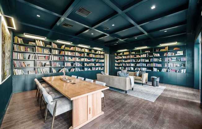 A room with a long table surrounded by bookshelves filled with books.