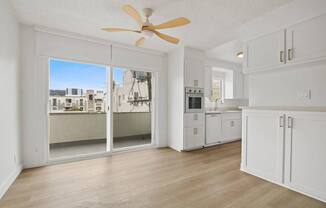 A white kitchen with a fan and sliding glass doors.
