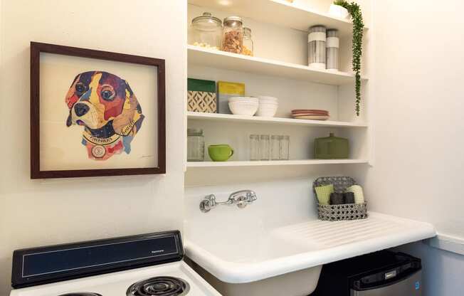 full size stove next to sink with built-in shelving above and mini fridge below