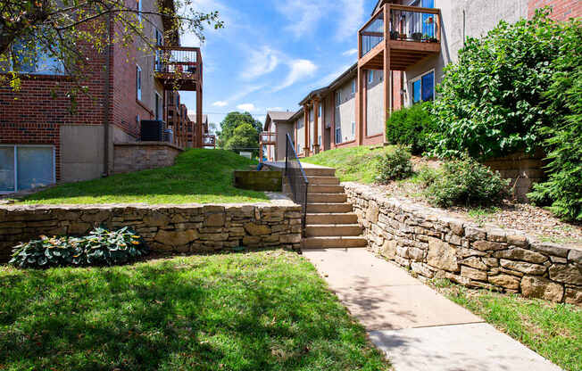 A stone wall and staircase lead up to a building with a balcony.