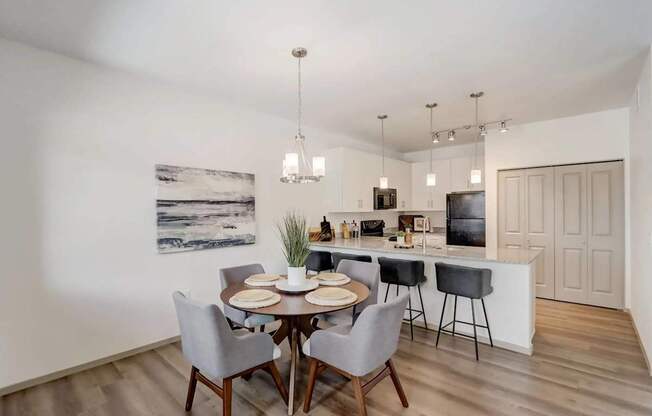A dining room with a table set for two and a kitchen area in the background.