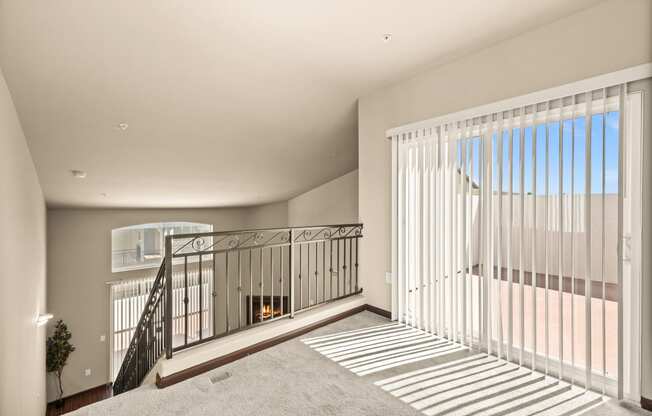 a living room with a staircase and a large window with white blinds